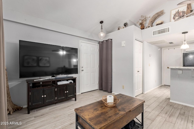 living room featuring lofted ceiling, visible vents, and light wood-style flooring