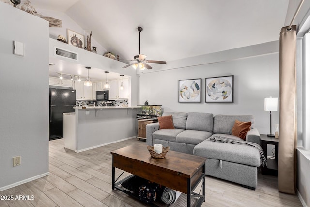 living area with baseboards, visible vents, a ceiling fan, vaulted ceiling, and light wood-type flooring