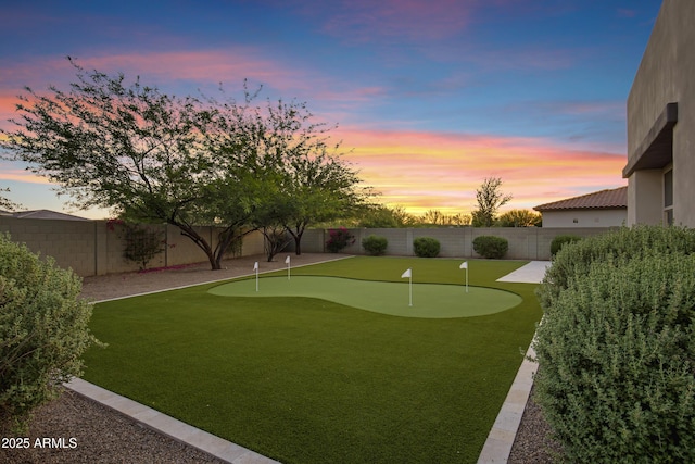 11717 W Red Hawk Dr, Peoria, AZ 85383 - yard at dusk with an area to practice putting and a fenced backyard