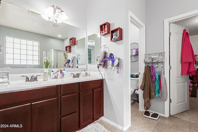 bathroom featuring tile patterned flooring, vanity, a shower with shower door, and toilet