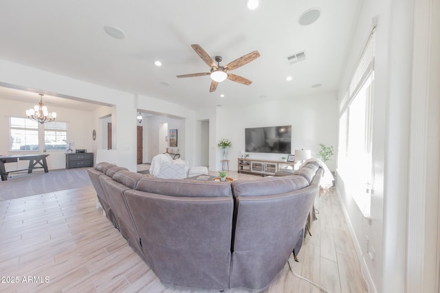 living room featuring ceiling fan with notable chandelier