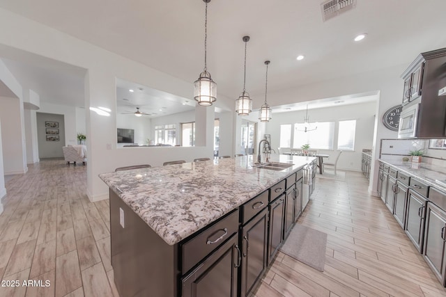 kitchen featuring pendant lighting, sink, a large island, ceiling fan, and dark brown cabinetry