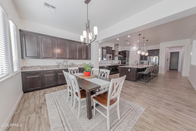 dining room with sink, light hardwood / wood-style floors, and a notable chandelier