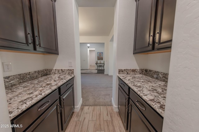 kitchen with light hardwood / wood-style floors, light stone countertops, and dark brown cabinetry