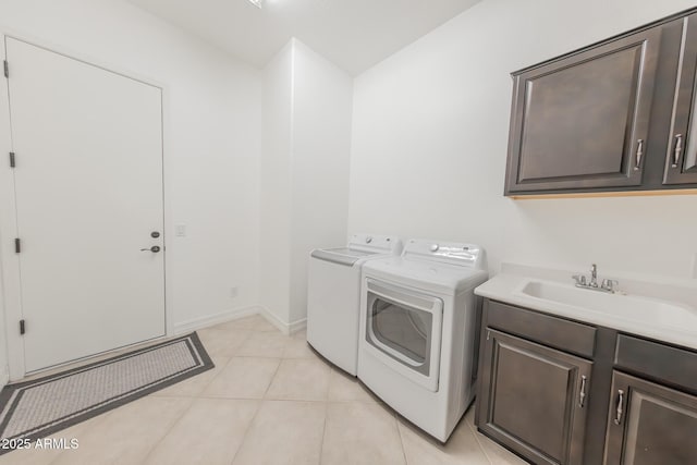 clothes washing area with sink, cabinets, washer and clothes dryer, and light tile patterned flooring