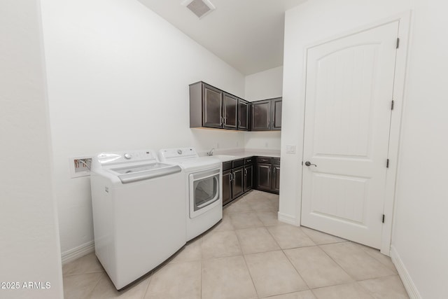 laundry area with light tile patterned flooring, cabinets, washing machine and clothes dryer, and sink