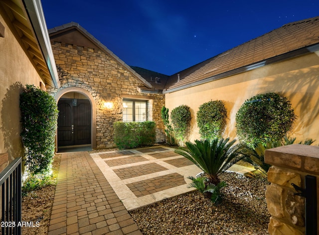 exterior entry at twilight featuring a patio area