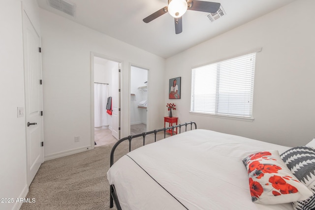 carpeted bedroom with ceiling fan, a walk in closet, and ensuite bathroom