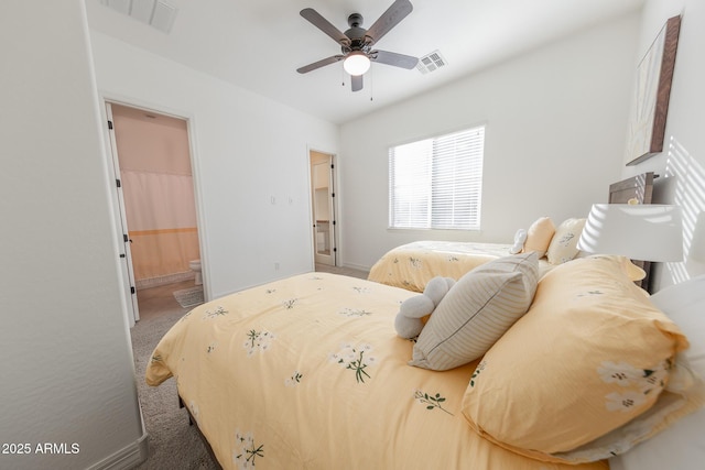 carpeted bedroom with a walk in closet, ensuite bath, and ceiling fan