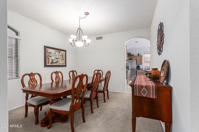 dining space with light carpet and an inviting chandelier