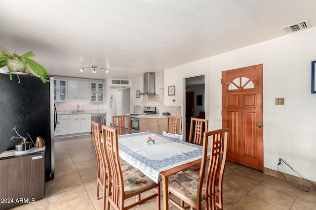 tiled dining room with a textured ceiling and sink