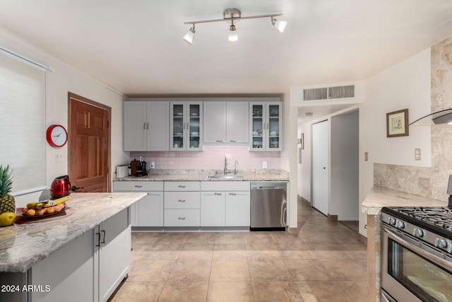 kitchen featuring light stone countertops, sink, stainless steel appliances, backsplash, and light tile patterned floors