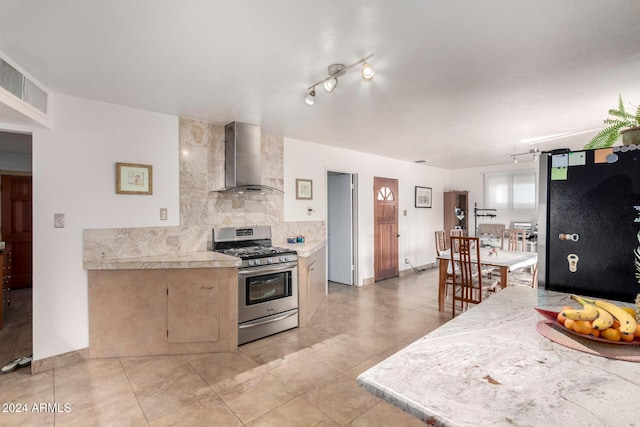 kitchen featuring backsplash, wall chimney exhaust hood, light tile patterned floors, and appliances with stainless steel finishes