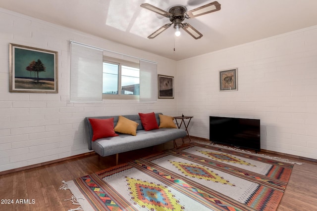 living room with dark hardwood / wood-style floors, ceiling fan, and brick wall