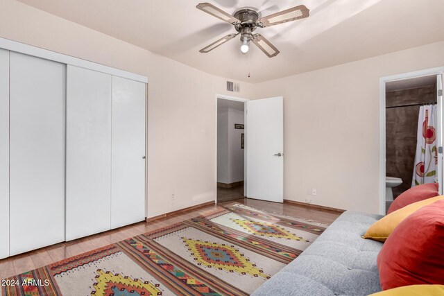 bedroom with hardwood / wood-style floors, ceiling fan, a closet, and ensuite bath