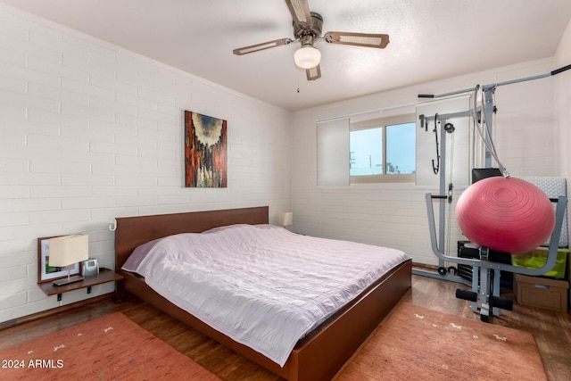 bedroom with ceiling fan, brick wall, and hardwood / wood-style flooring