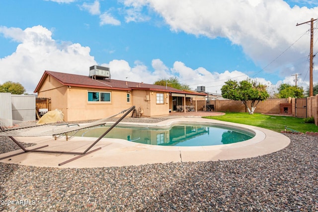 view of pool with a lawn, cooling unit, and a patio