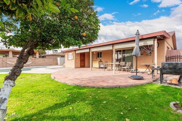 rear view of property with a yard, a fenced in pool, and a patio area