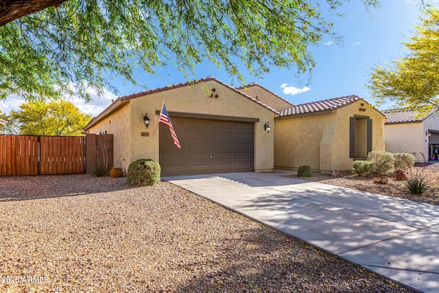 mediterranean / spanish house featuring a garage, stucco siding, a gate, concrete driveway, and a tile roof