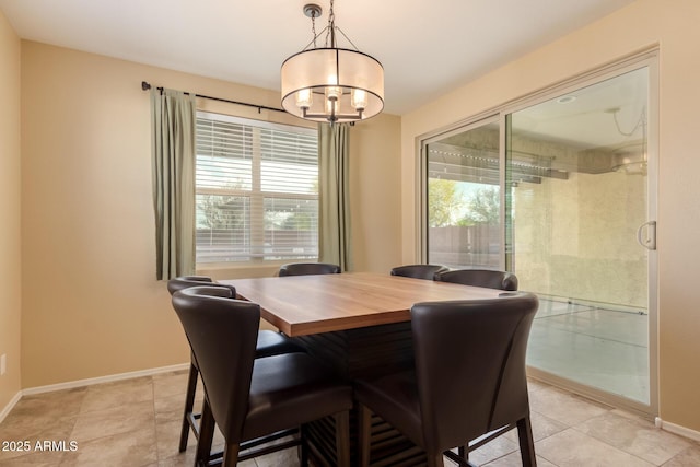 dining room featuring an inviting chandelier, baseboards, light tile patterned floors, and a wealth of natural light