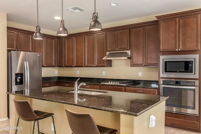 kitchen featuring visible vents, appliances with stainless steel finishes, a sink, dark stone counters, and under cabinet range hood