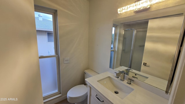 bathroom featuring toilet, a shower with shower door, and vanity