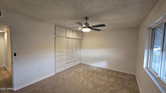 unfurnished bedroom featuring a closet, ceiling fan, light colored carpet, and a textured ceiling