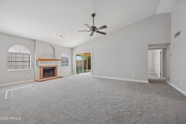 unfurnished living room with vaulted ceiling, a brick fireplace, ceiling fan, and light colored carpet