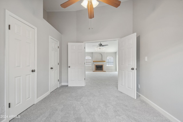 unfurnished room featuring a high ceiling, ceiling fan, and light carpet