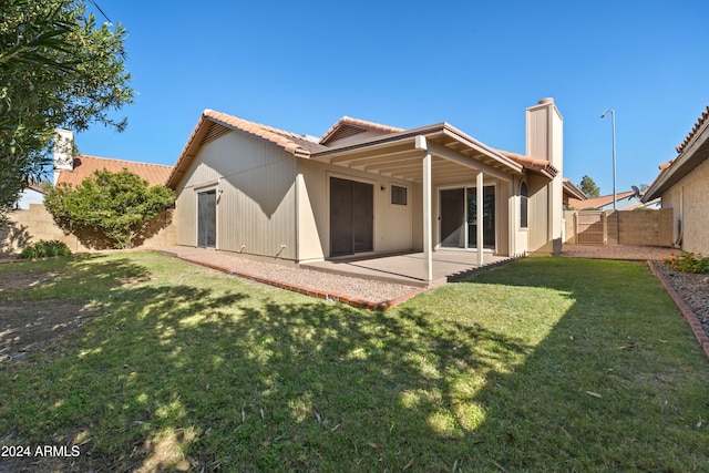 back of property with a yard and a patio