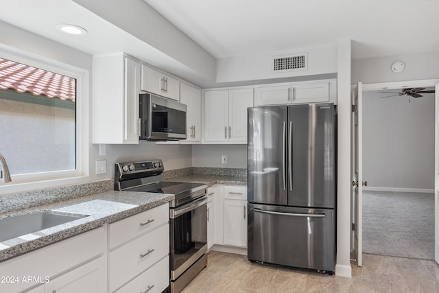 kitchen featuring white cabinetry, a wealth of natural light, light stone countertops, and stainless steel appliances