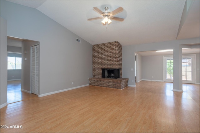 unfurnished living room with lofted ceiling, a fireplace, a wealth of natural light, and light hardwood / wood-style flooring