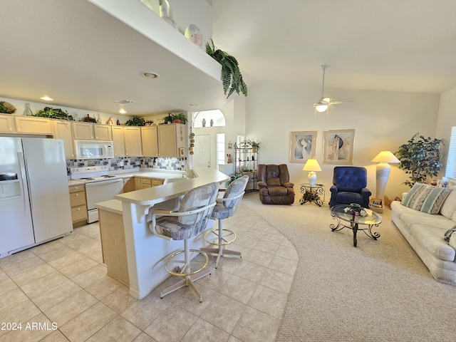 kitchen with decorative backsplash, kitchen peninsula, a kitchen breakfast bar, white appliances, and light brown cabinets