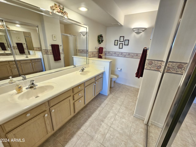 bathroom featuring tile patterned floors, a shower with door, vanity, and toilet