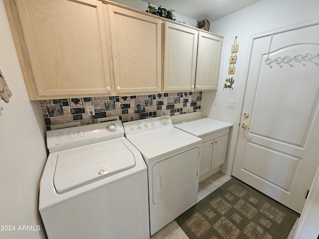 laundry area with washing machine and clothes dryer, cabinets, and dark tile patterned flooring