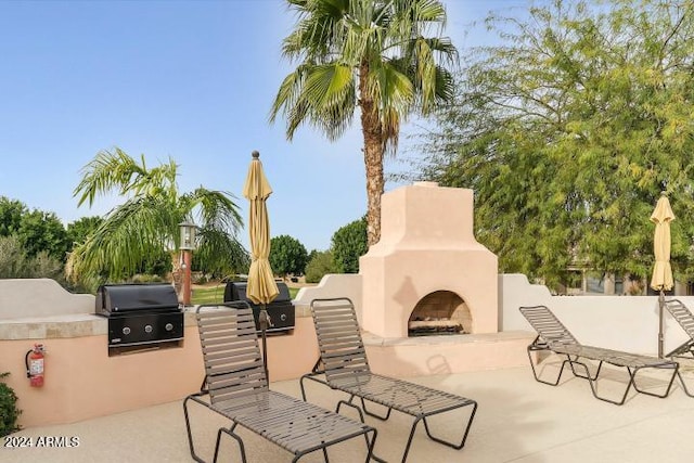 view of patio featuring an outdoor kitchen, exterior fireplace, and a grill