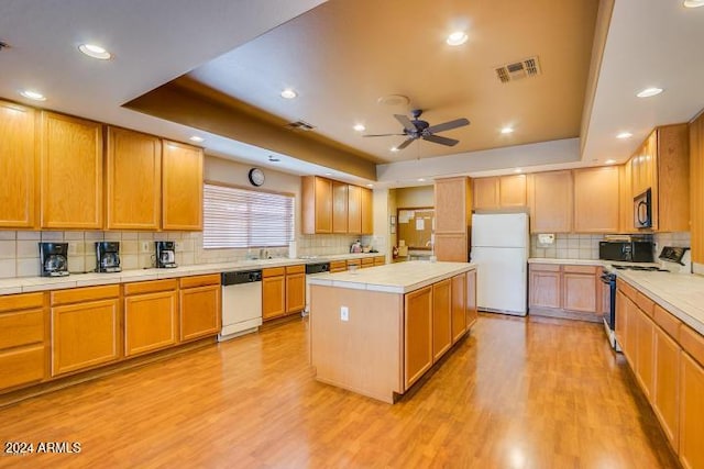 kitchen featuring ceiling fan, a center island, light hardwood / wood-style floors, white appliances, and a tray ceiling