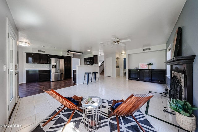 4306 E Raven Rd, Phoenix, AZ 85044 - living area with light tile patterned floors, a fireplace with raised hearth, a ceiling fan, and baseboards