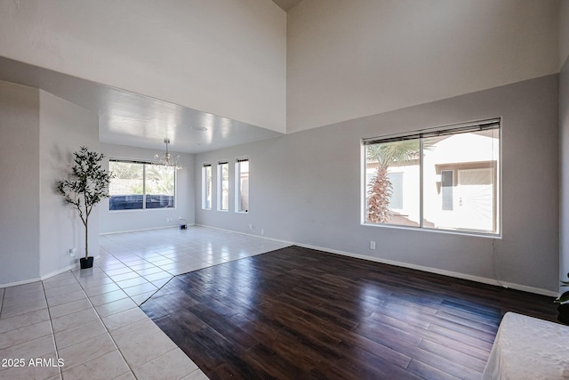 4306 E Raven Rd, Phoenix, AZ 85044 - unfurnished living room with a chandelier, baseboards, wood finished floors, and a towering ceiling