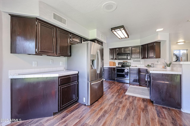 4306 E Raven Rd, Phoenix, AZ 85044 - kitchen with appliances with stainless steel finishes, a sink, dark brown cabinetry, dark wood-type flooring, and tile countertops
