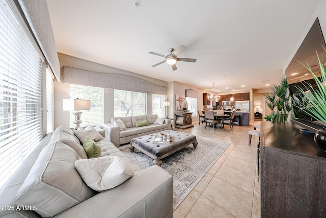 living area featuring light tile patterned floors, recessed lighting, and ceiling fan with notable chandelier