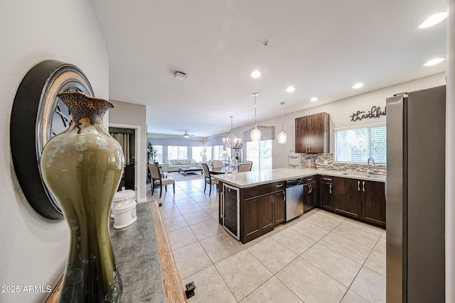 kitchen featuring open floor plan, a peninsula, appliances with stainless steel finishes, light tile patterned floors, and dark brown cabinets