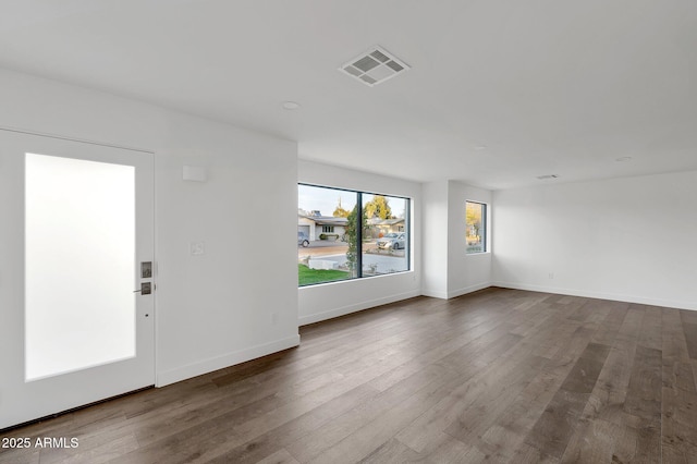 spare room with baseboards, visible vents, and wood finished floors