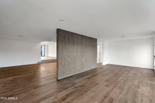 unfurnished living room featuring wood finished floors, visible vents, and baseboards