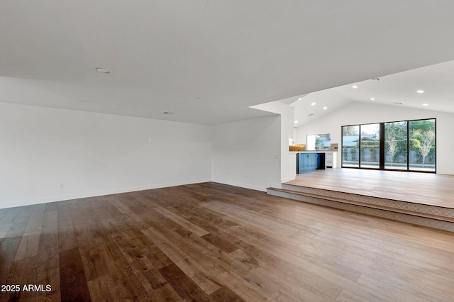 unfurnished living room with lofted ceiling, baseboards, wood finished floors, and recessed lighting