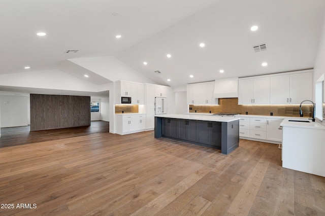 kitchen featuring a large island, light countertops, visible vents, custom range hood, and open floor plan