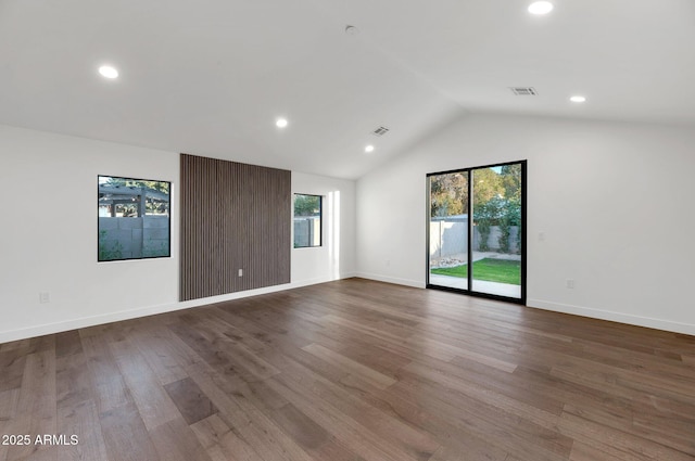 empty room with lofted ceiling, visible vents, a wealth of natural light, and wood finished floors