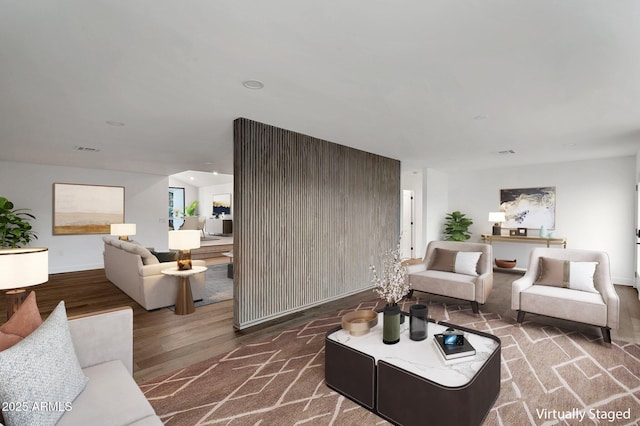 living area with baseboards, visible vents, and wood finished floors