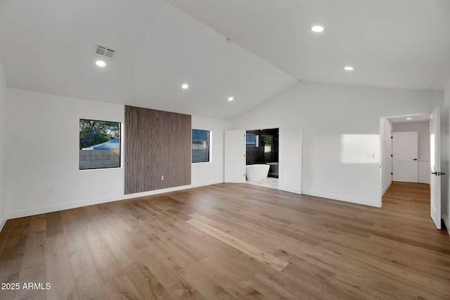 unfurnished living room with recessed lighting, visible vents, light wood-style floors, high vaulted ceiling, and baseboards