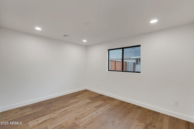 empty room with light wood-style floors, visible vents, baseboards, and recessed lighting